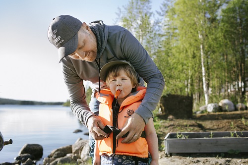 Bild på barn med flytväst och vuxen som knäpper den