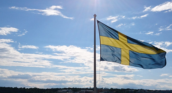 Bild på vajande svensk flagga mot himmel