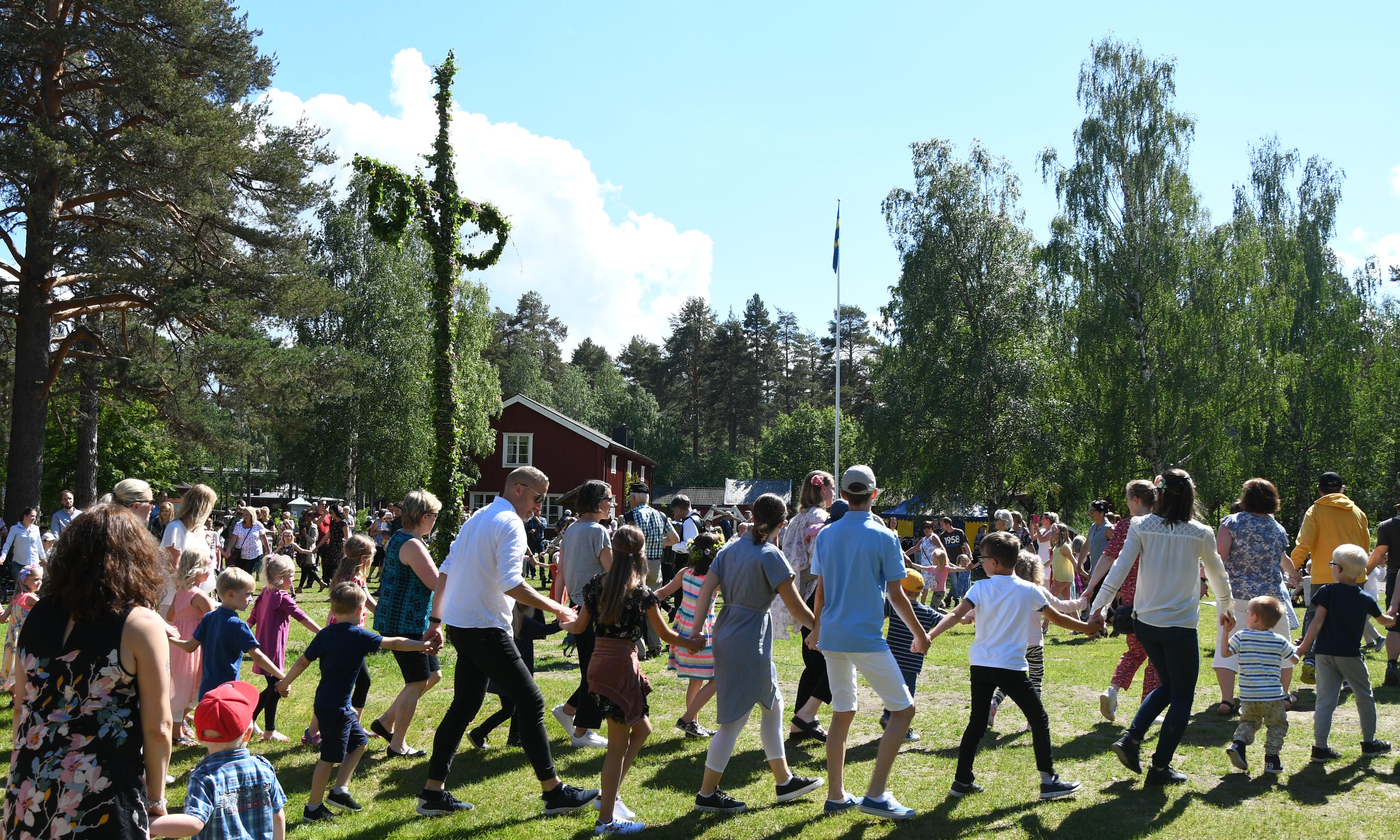 folk som dansar runt en midsommarstång