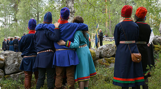 Ungdomar i samiska kläder håller om varandra