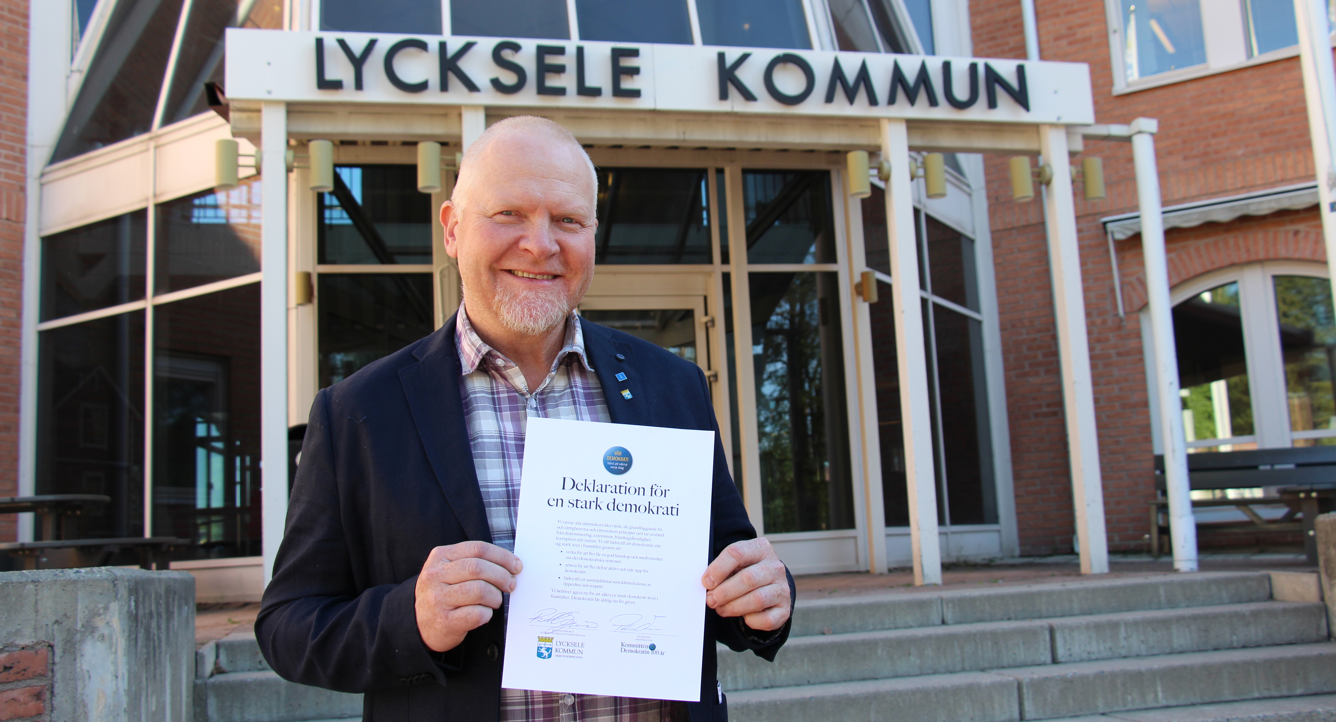 Roland Sjögren som håller i demokratideklrationen. Står framför stadshuset. 