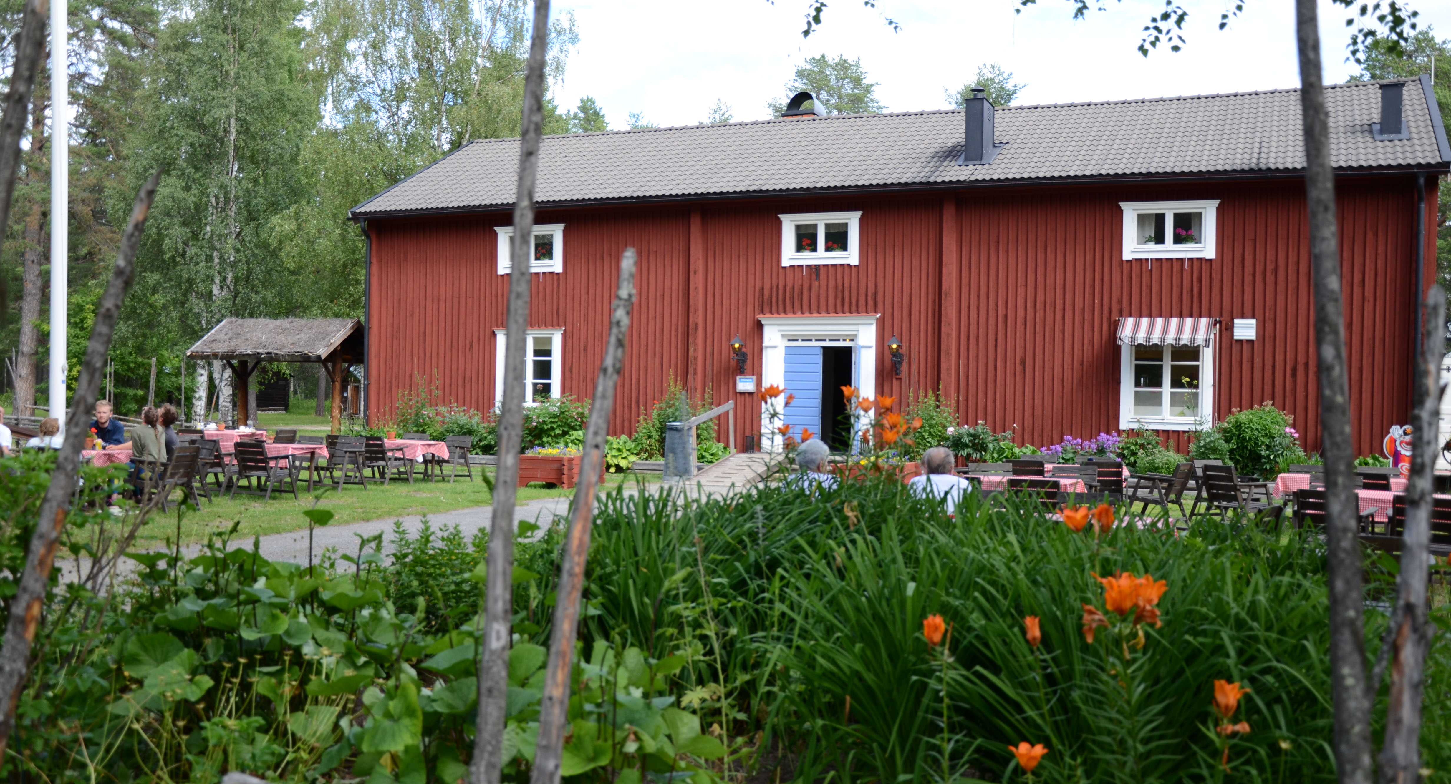bild på Ruselegården, röd byggnad i trä med blommor framför