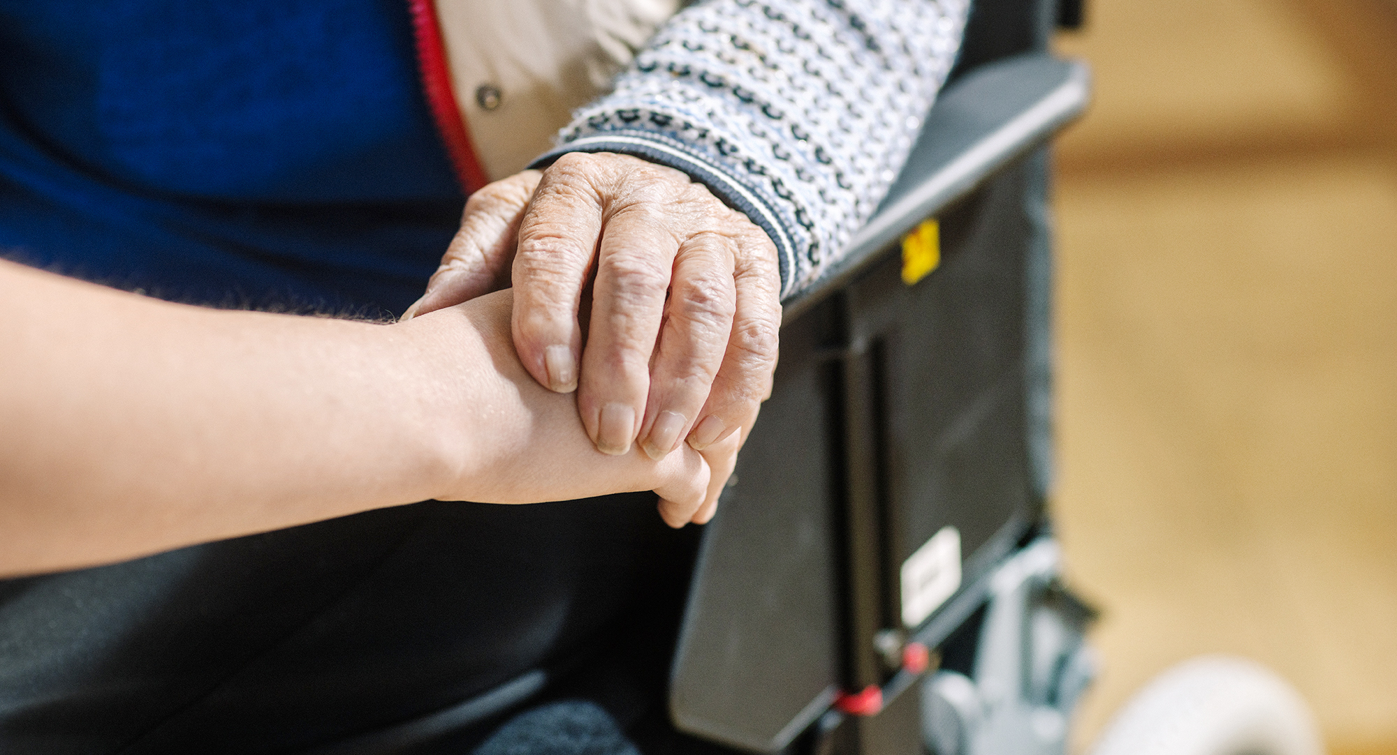 Bild på två som håller varandra i hand. En äldre och en yngre. 