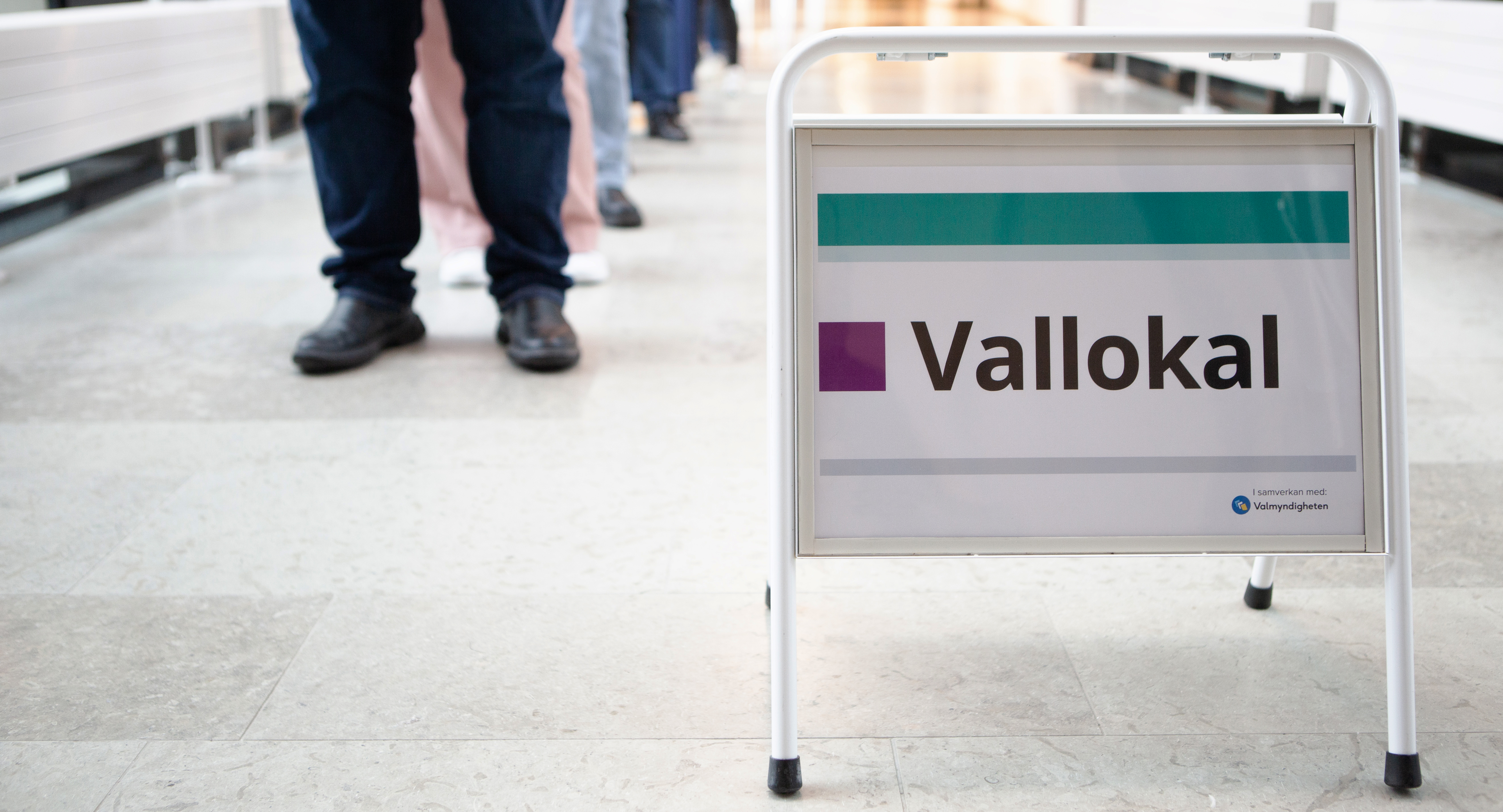 Bild på skylt där det står EU-valet och människor i bakgrunden som står i kö.