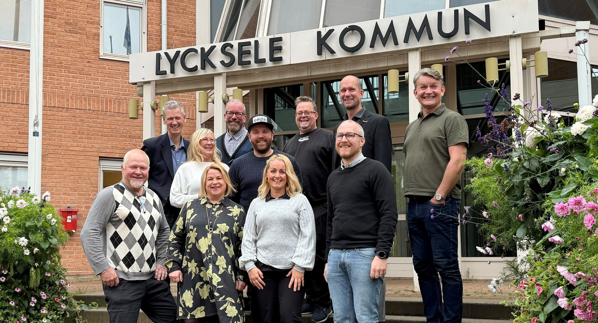 En grupp med personer såtr under en skylt där det står Lycksele kommun och ler.