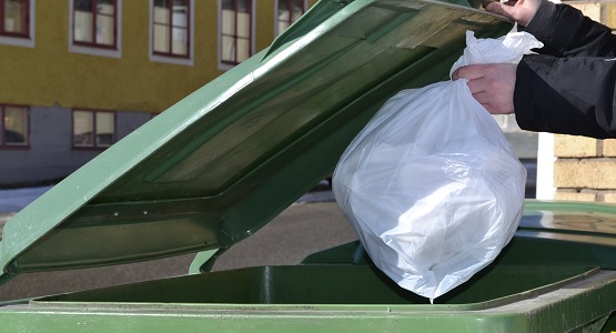 Avfallspåse läggs i avfallskärlet