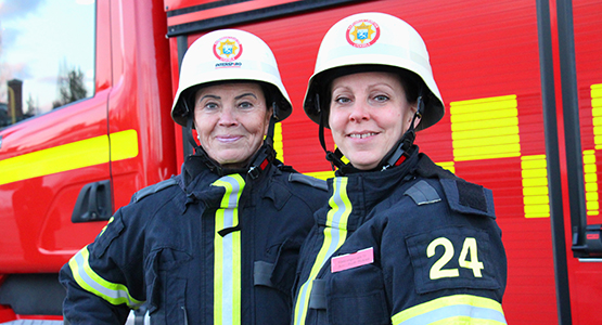 bilder på två kvinnor inom räddningstjänsten vid en brandbil